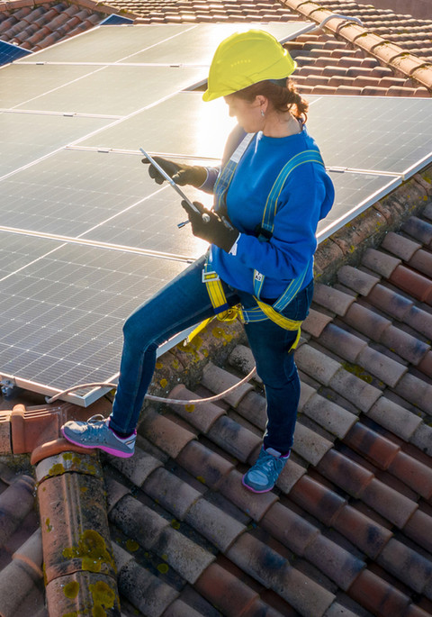 Fachkraft bei der Solarmontage auf dem Dach mit Sicherheitsausrüstung